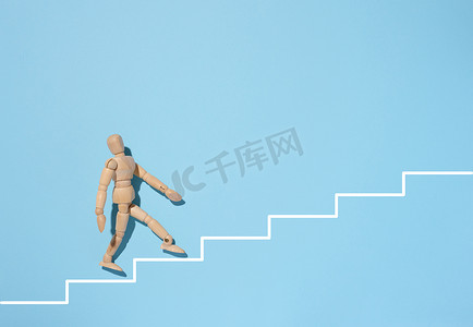 一个木制人体模型在蓝色背景上走上漆成白色的楼梯。