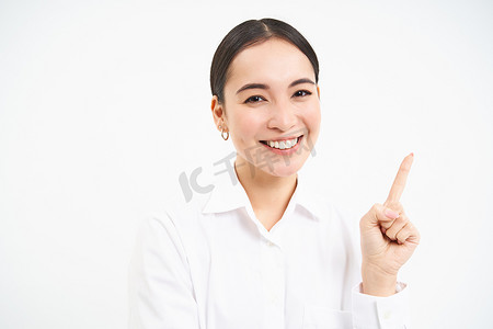 成功的韩国女商人，手指向右，在横幅上展示广告，站在白色背景上