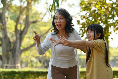 快乐的亚洲小孩和祖母在公园散步时玩得很开心。