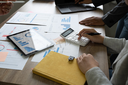 业务人员小组分析业务运营费用的摘要图表报告和有关公司财务报表的工作数据。
