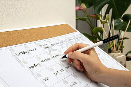 女性在月度规划师上用记号笔写满了下个月的约会和计划。