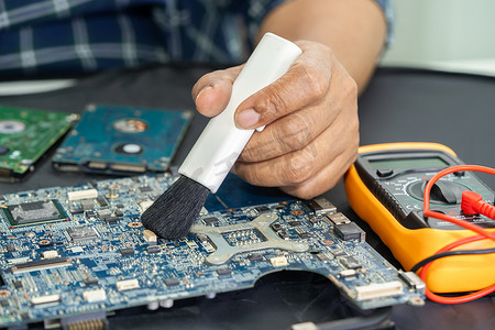 亚洲技术人员用刷子、硬件、手机、升级概念维修和清洁智能手机电子技术的脏微电路主板。