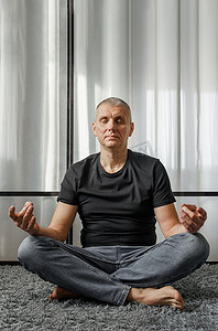 下班休息时，一名男子在瑜伽垫上盘膝冥想。