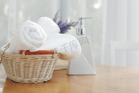 一瓶液体肥皂和白毛巾放在浴室的桌子上