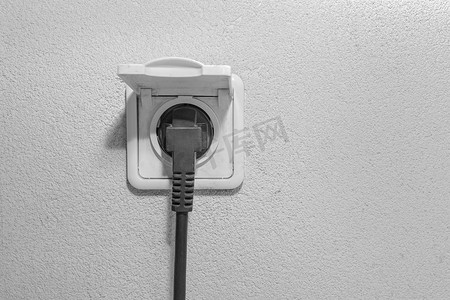 我是插座摄影照片_白背景墙上家用电源插座的黑插头电缆线卡住