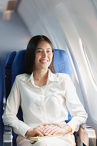 美丽的亚洲女商人在豪华飞行中快乐而微笑。