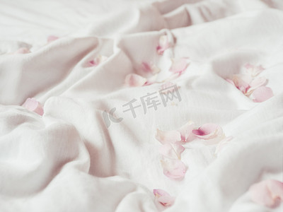 皱巴巴的白色织物上的粉红色玫瑰花瓣。