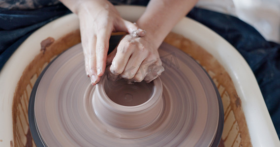 陶艺古文化摄影照片_陶艺、艺术和手放在陶轮上，艺术家在创意课、车间或工作室中旋转粘土。