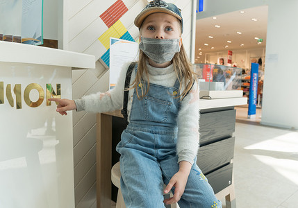 一个在购物中心戴着防护性医用口罩的女婴