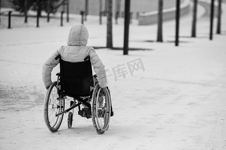 身无分文摄影照片_冬天，无家可归的妇女坐在轮椅上。