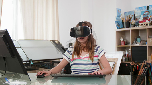 十几岁的女孩用鼠标、键盘和虚拟现实耳机玩游戏