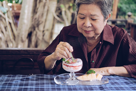 吃草莓潘纳婴儿床的亚洲老老年妇女