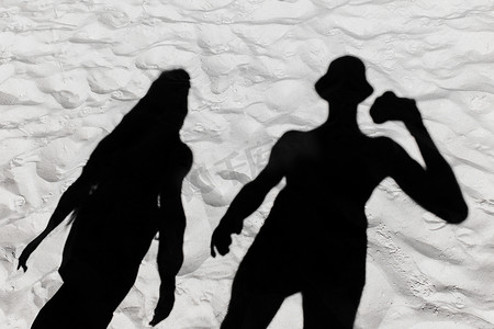 沙滩背景摄影照片_白色沙滩背景上一个男人和一个女孩的深黑色剪影