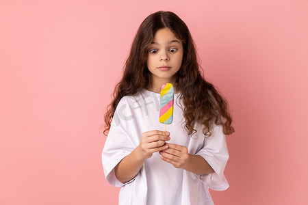 震惊的小女孩拿着美味的冰淇淋，用惊讶的表情看着甜点。