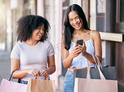 女性或朋友在网站、移动应用程序或社交媒体上购物、智能手机和城市街道促销、零售时尚的销售或折扣。