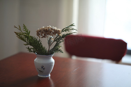 深色餐桌背景摄影照片_柔和的家居装饰、白色水罐、深色复古餐桌背景上带花的花瓶。