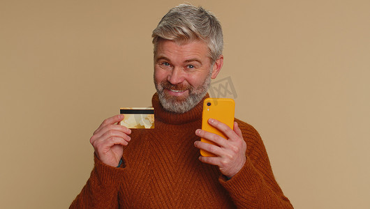 老人在转账时使用信用卡和智能手机购买网上购物