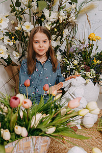 两个女孩在一个美丽的复活节照片区，那里有鲜花、鸡蛋、小鸡和复活节兔子。