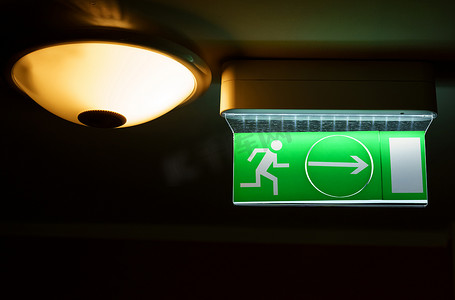 一个绿色警示灯板，描绘了一个带着箭头的跑步者。