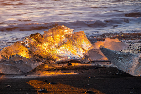 日落时在黑色火山沙滩上闪耀的纯冰。