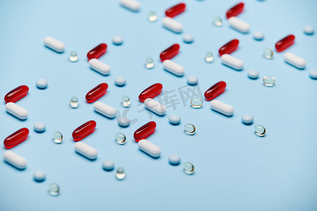 布局与红色明胶半透明胶囊和药丸排列在蓝色背景上的图案。