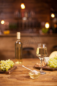 一碗金蜂蜜罐，旁边是木桌上的新鲜葡萄和胡桃