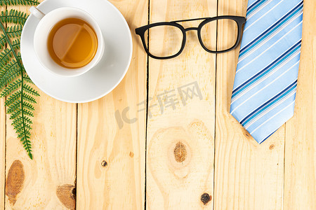 父亲节快乐背景概念，蓝色领带、眼镜和木制背景上的茶杯，带有文本复制空间。