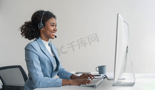 在无线耳机中关闭呼叫中心操作员与客户交谈，在耳机中与麦克风的女性在客户支持服务中通过电话咨询客户，看着电脑屏幕