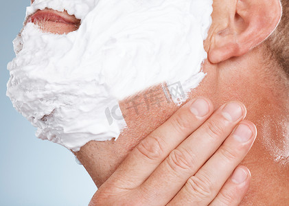 脱毛膏摄影照片_工作室里男人的脸、剃须膏和手被蓝色背景隔离，用于脱毛。