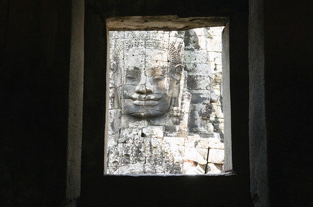 东南亚人摄影照片_透过废墟之窗看到的石面雕塑