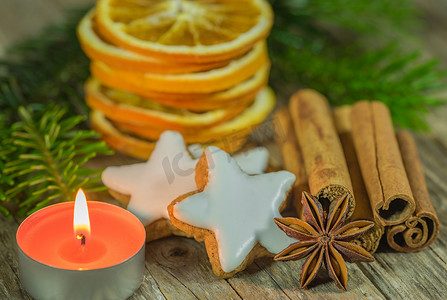 木桌上放着星星饼干、肉桂、茴香、橙片和蜡烛的圣诞静物