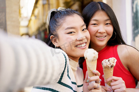 快乐的亚洲女友拿着冰淇淋自拍