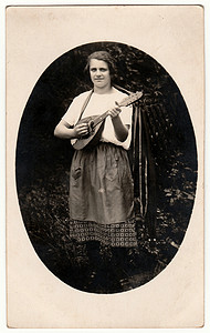 复古照片显示一位女士在户外弹奏曼陀林。