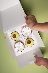 糕点海报摄影照片_女手打开一个盒子，里面装着不同的蛋糕甜点送货上门