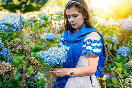 穿着传统中美洲民间服装的妇女在苗圃里捧着鲜花。