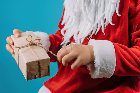 穿着圣诞老人服装的男孩的手拉着一串包裹好的礼品盒。