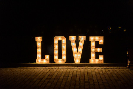 字母装饰摄影照片_在婚礼招待会上用大字母照亮的爱情标志