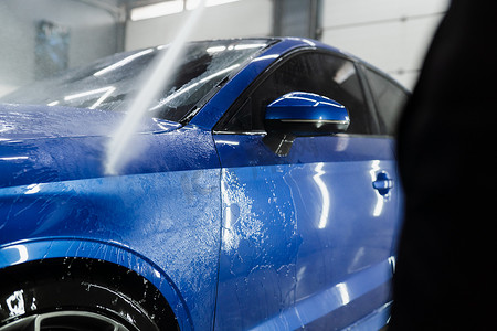 洗车汽车摄影照片_洗车机倒水进行全身洗车。