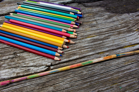 木制背景上的彩色铅笔和彩绘的竹签。