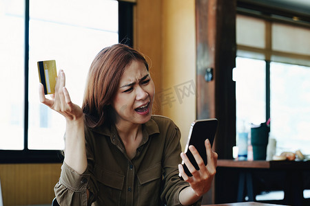 网上贷款摄影照片_一位亚洲少女的肖像，她对信用卡在使用手机网上购物时被禁止表示不满
