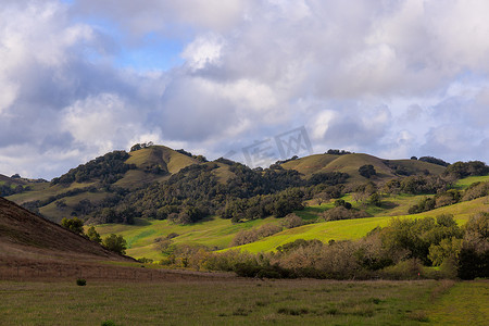 连绵的山摄影照片_北加州风景中美丽的绿色连绵起伏的丘陵上的阳光