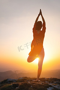 树剪影剪影摄影照片_女人站在山里对着太阳做瑜伽姿势，一个运动型女人的剪影