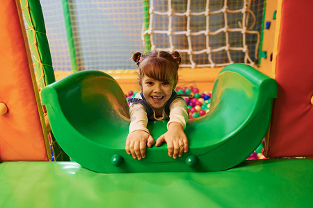 穿着休闲服的快乐小女孩在儿童游戏中心玩得开心