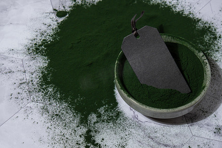 功能食品摄影照片_碗中蓝绿藻小球藻和螺旋藻粉，空纸条模拟复制空间。