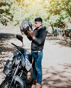 年轻的骑摩托车的人戴上安全头盔，骑摩托车的人戴上头盔。