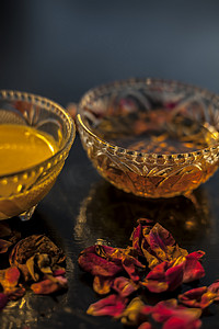 玻璃碗中黑色光滑表面上的 Ayurvedic 保湿面膜，配有一些酥油或澄清黄油、蜂蜜和包装。