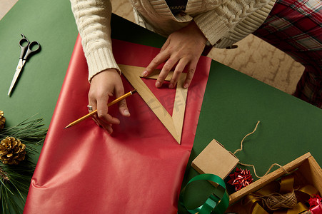 使用木尺的顶视图女性计算包装圣诞礼物所需的包装材料量
