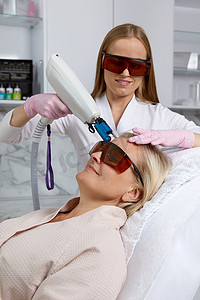 戴着防护眼镜在美容诊所接受激光治疗的中年妇女