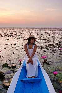 泰国乌隆他尼的红莲海 Kumphawapi 满是粉红色的花朵，亚洲女性在一艘船上。