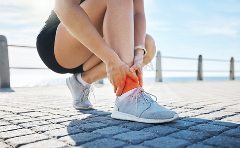 红色海滩摄影照片_锻炼、身体训练受伤或户外锻炼后，在海滩上脚踝疼痛的健身、手或跑步者。